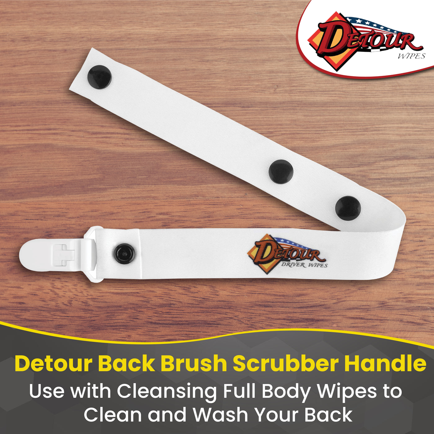 Detour Wipes back brush scrubber handle shown on a wooden surface, featuring adjustable snaps and Detour branding with text about using it with full body cleansing wipes.”
