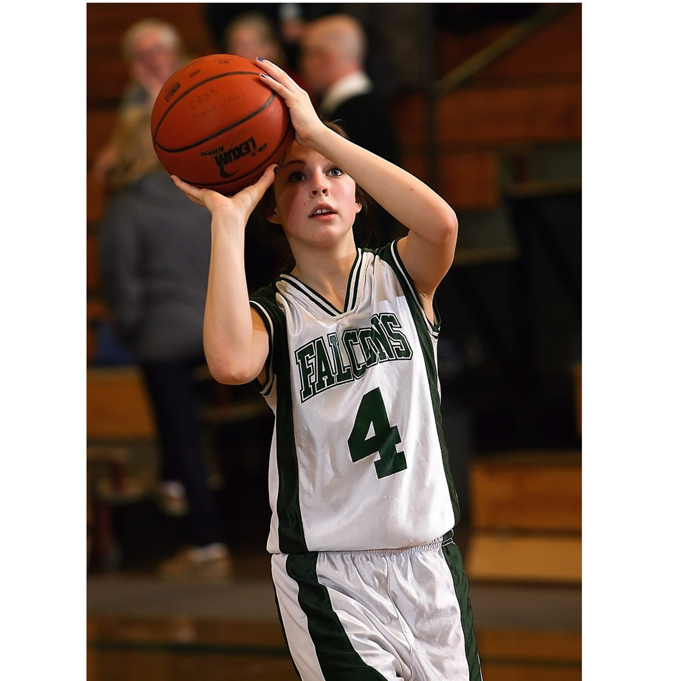 Young basketball player in a Falcons number 4 jersey preparing to shoot during a game in a school gym.”
